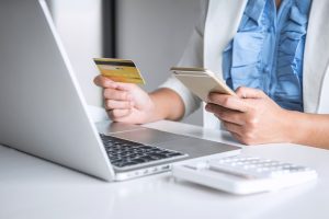 woman looking at credit card and making payment online